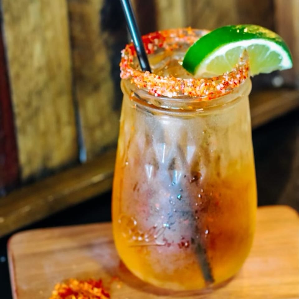Golden cocktail with lime and a colorful seasoned rim