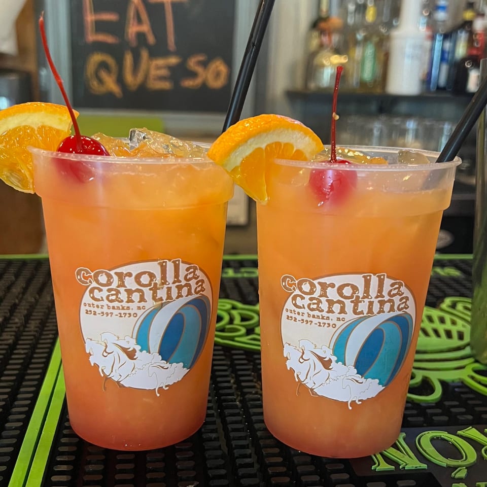 Two orange cocktails in Corolla Cantina cups